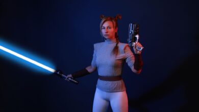 A woman dressed in sci-fi costume wields a lightsaber and blaster in a dramatic studio setting.