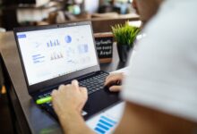 Focused business analysis with charts and graphs on a laptop in a modern office setting.