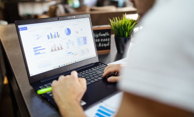 Focused business analysis with charts and graphs on a laptop in a modern office setting.