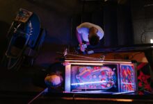 Overhead view of pinball game being set up in a retro arcade setting.