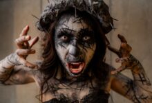 A dramatic portrait of a person with surreal horror makeup and a spiked headpiece, evoking a gothic atmosphere.