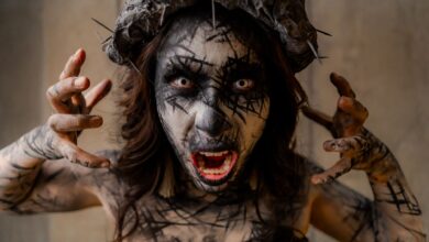 A dramatic portrait of a person with surreal horror makeup and a spiked headpiece, evoking a gothic atmosphere.