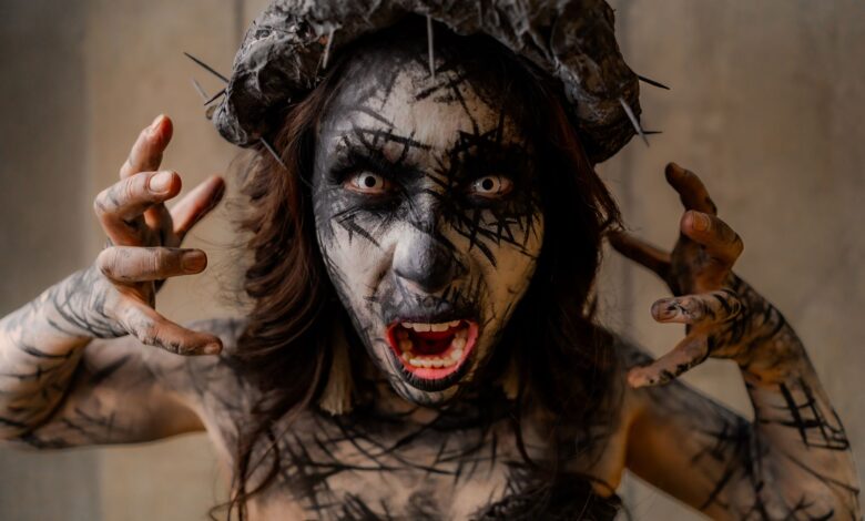 A dramatic portrait of a person with surreal horror makeup and a spiked headpiece, evoking a gothic atmosphere.
