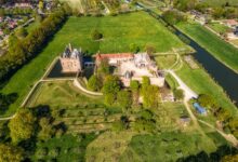 A stunning aerial view of a historic castle surrounded by lush greenery and farmland.