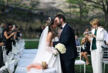 A newlywed couple shares a romantic kiss during an outdoor wedding ceremony.