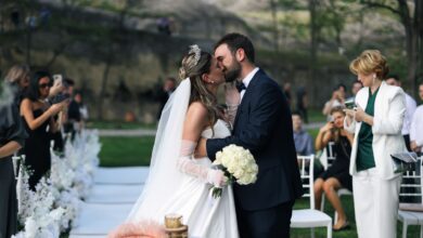 A newlywed couple shares a romantic kiss during an outdoor wedding ceremony.