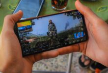 From above crop anonymous male playing captivating video game on contemporary mobile phone near table on terrace