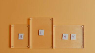 Artistic arrangement of letters spelling 'Slay' with glass frames on a vibrant orange backdrop.