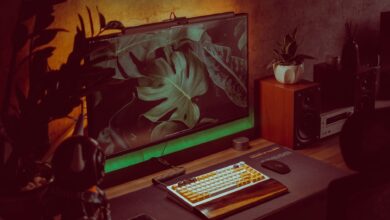 Stylish home office setup with a monitor, keyboard, and plants creating a cozy working environment.