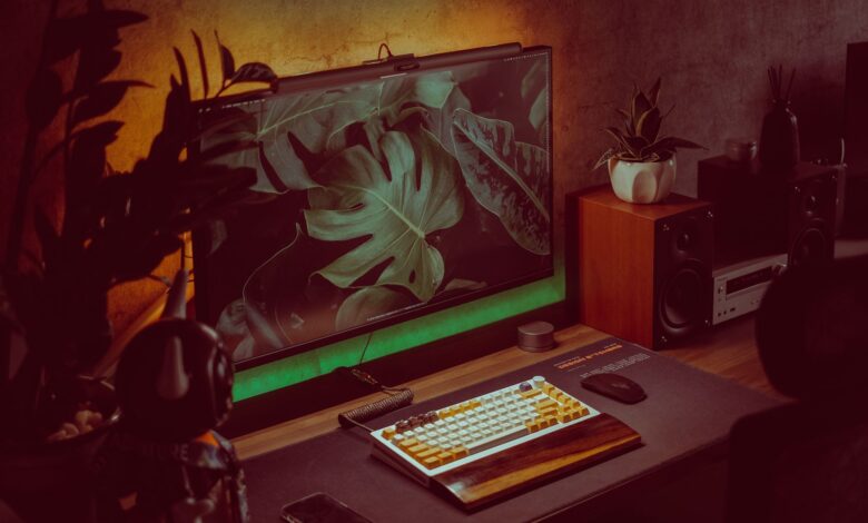 Stylish home office setup with a monitor, keyboard, and plants creating a cozy working environment.