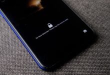 Mobile phone with no face detected message on lock screen on a textured fabric surface.
