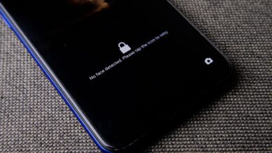 Mobile phone with no face detected message on lock screen on a textured fabric surface.