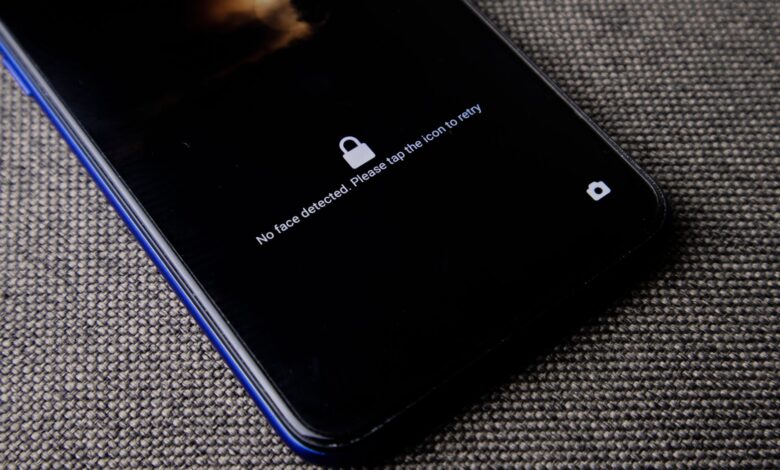 Mobile phone with no face detected message on lock screen on a textured fabric surface.