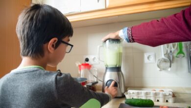 A father and son team up to make a healthy smoothie in a modern kitchen.