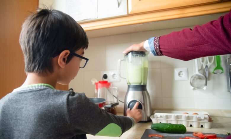 A father and son team up to make a healthy smoothie in a modern kitchen.