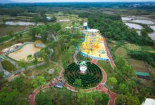 A colorful aerial view of an amusement park in Jiujiang, China, surrounded by lush greenery.