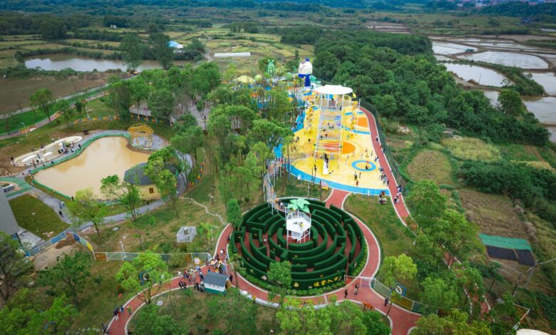 A colorful aerial view of an amusement park in Jiujiang, China, surrounded by lush greenery.