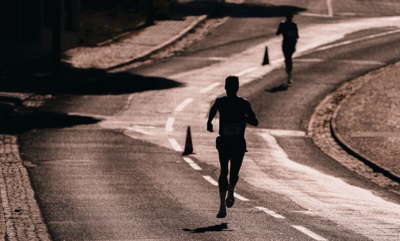 Silhouette of a runner on a street during a race. Captures athletic determination and movement.