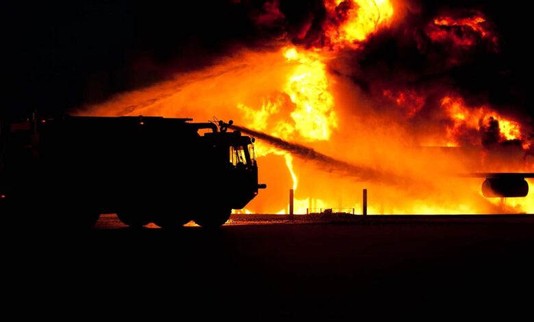 Dramatic image of a fire truck silhouette against a massive blaze, showcasing emergency response.