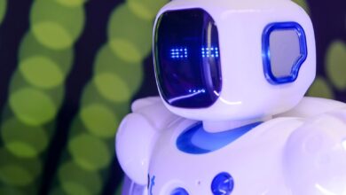 Close-up of a modern humanoid robot with glowing blue features on a green abstract background.