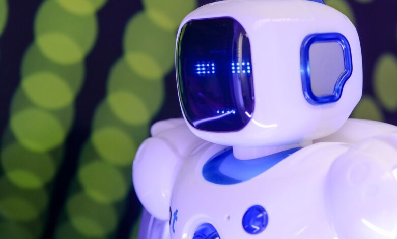 Close-up of a modern humanoid robot with glowing blue features on a green abstract background.