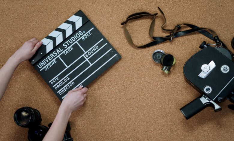 Top view of classic filmmaking tools including a slate and vintage camera on a cork surface.