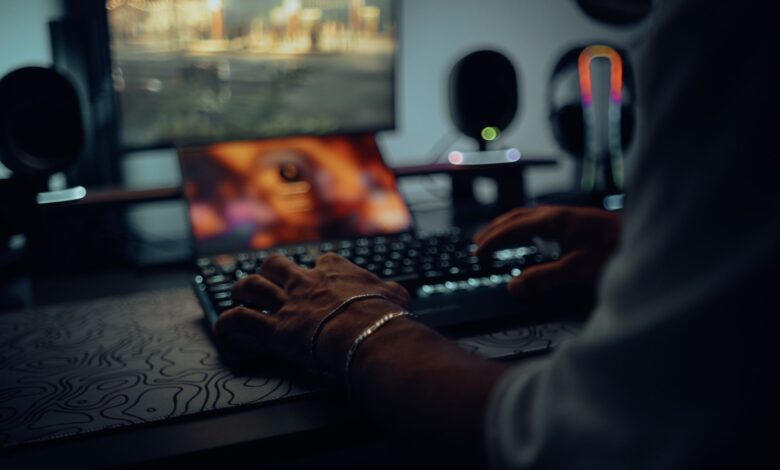Focused man typing in a dimly lit room, creating a moody atmosphere.
