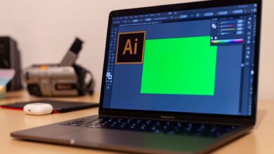 Close-up of a MacBook Pro with Adobe Illustrator open on a desk, showcasing creative workspace essentials.