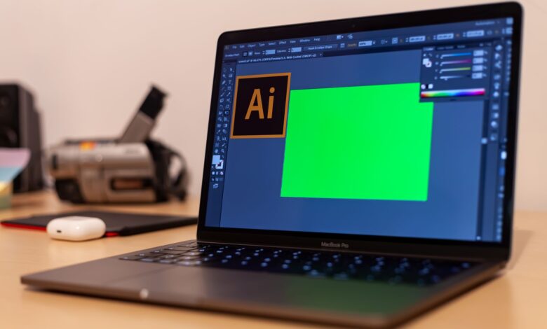 Close-up of a MacBook Pro with Adobe Illustrator open on a desk, showcasing creative workspace essentials.