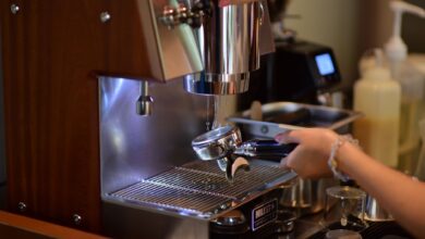 Barista hands preparing espresso with a coffee machine in a cozy cafe setting.