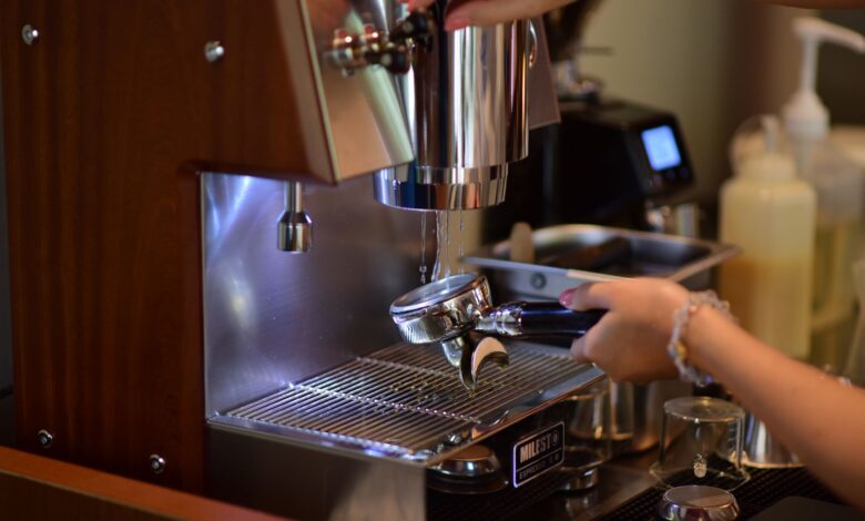 Barista hands preparing espresso with a coffee machine in a cozy cafe setting.