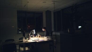 A man working late at night in an office, illuminated by desk light.