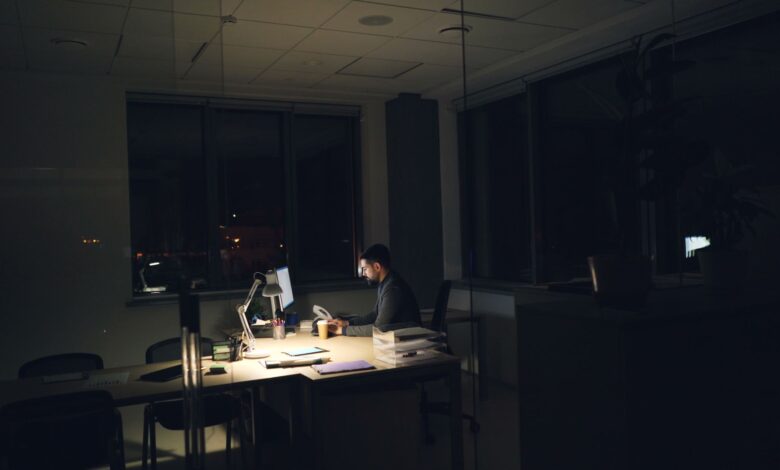 A man working late at night in an office, illuminated by desk light.