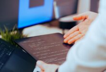 Software developer analyzing code on a tablet in a modern office workspace.