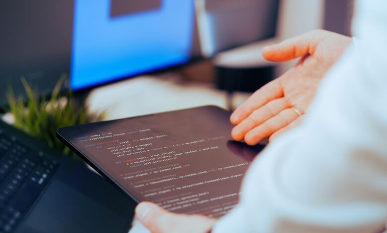 Software developer analyzing code on a tablet in a modern office workspace.
