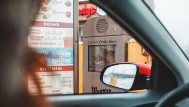 Blurred driver choosing food from menu and telling order to drive thru speaker post