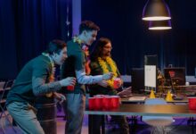 Group of male colleagues enjoying a fun beer pong game during an office party night.