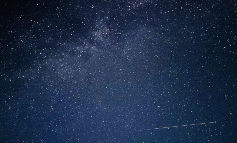 A clear night sky filled with stars and a meteor streaking across.