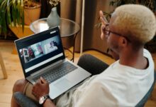 Blonde-haired man engaged in a video call, sitting indoors with a laptop.
