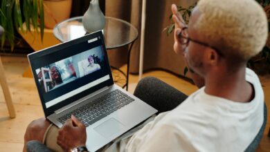 Blonde-haired man engaged in a video call, sitting indoors with a laptop.
