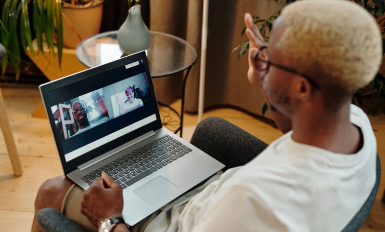 Blonde-haired man engaged in a video call, sitting indoors with a laptop.