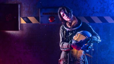 Portrait of a woman in a space suit in a dark, futuristic setting with dramatic lighting.