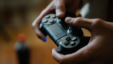 Crop anonymous male pressing buttons on console controller while playing video game in house on blurred background