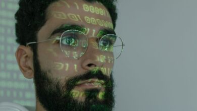 A bearded man with digital binary code projected on his face, symbolizing cybersecurity and technology.