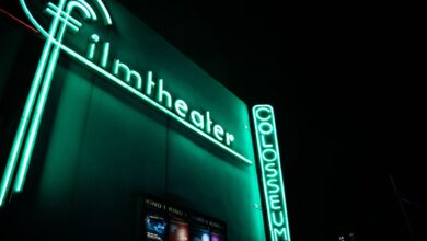 Vibrant neon film theater sign glowing at nighttime.