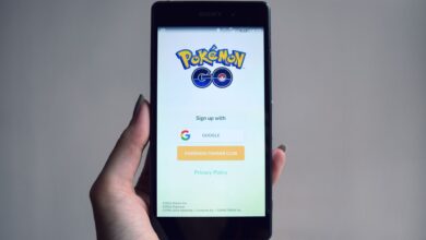 Smartphone displaying Pokémon Go app sign-in screen, held in hand.