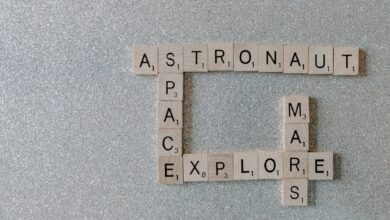 Wooden Scrabble tiles forming words related to space exploration on a glittery surface.
