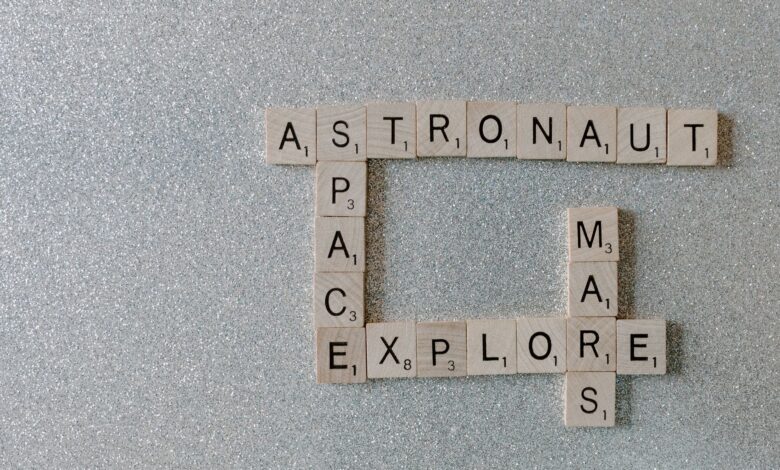 Wooden Scrabble tiles forming words related to space exploration on a glittery surface.