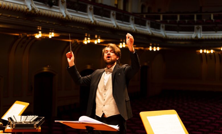 Orchestra conductor passionately leading a performance in an elegant concert hall.