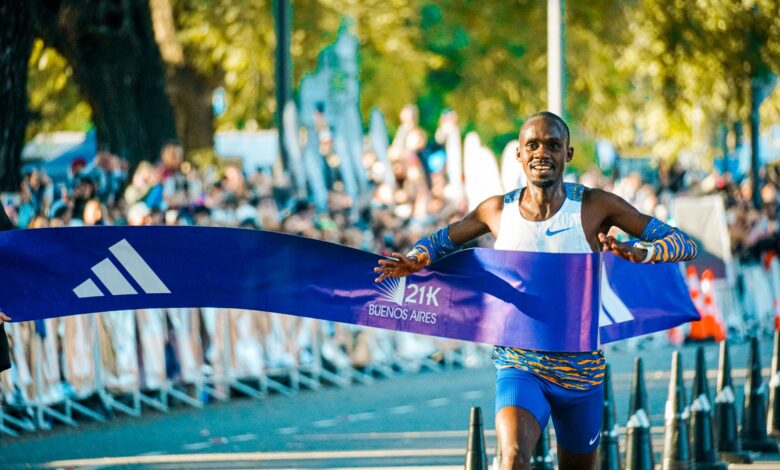 Male athlete crossing the finish line at the Buenos Aires marathon in a lively outdoor event.